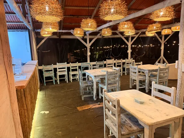Barra de guadua iluminada y mesas del restaurante, con luces de jardín al fondo