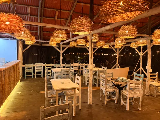 Salón del restaurante de noche: mesas y sillas de madera bajo las lámparas de fibra