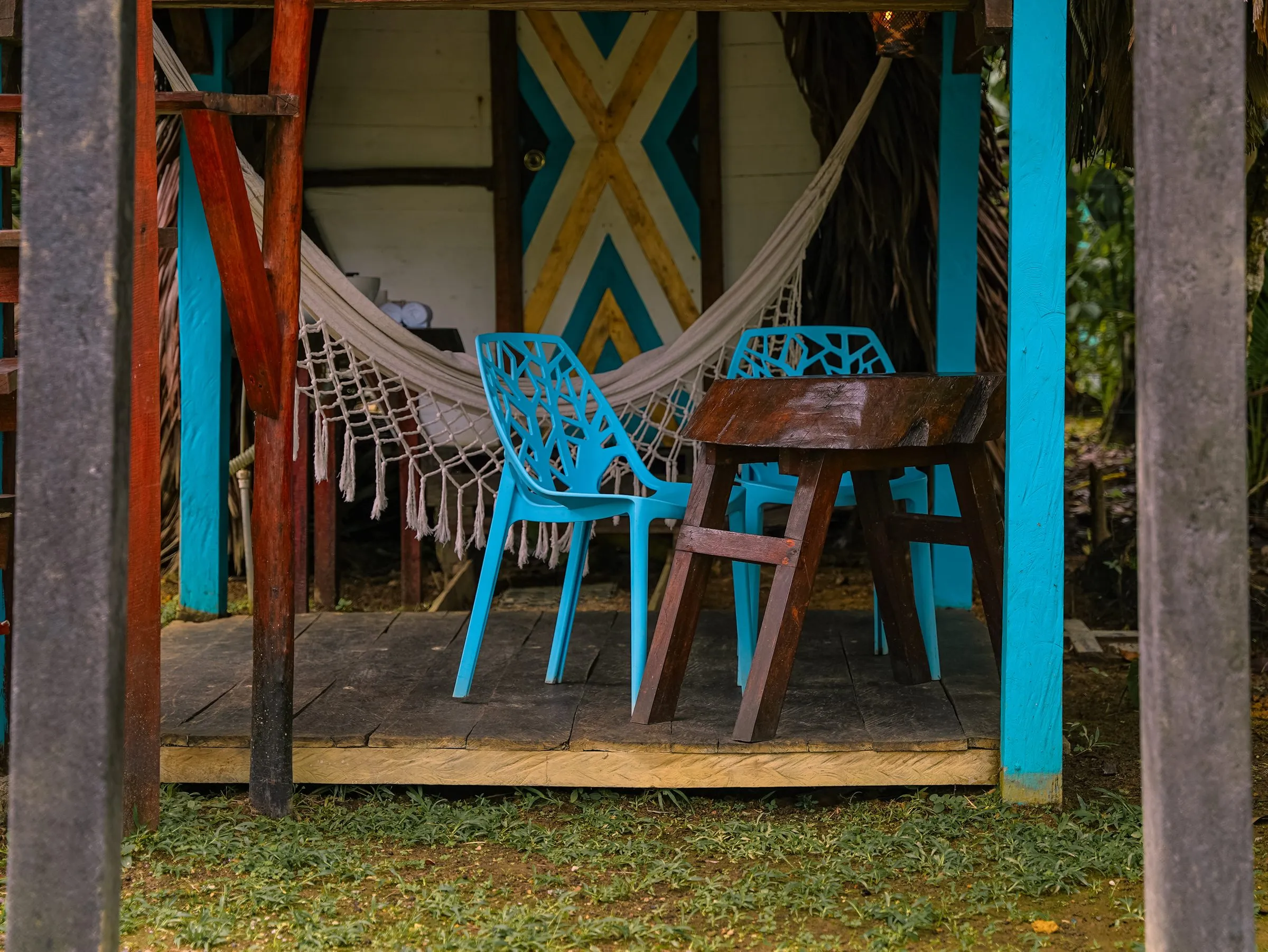 Terraza del Bungalow Mini 1 con hamaca tejida y sillas azules