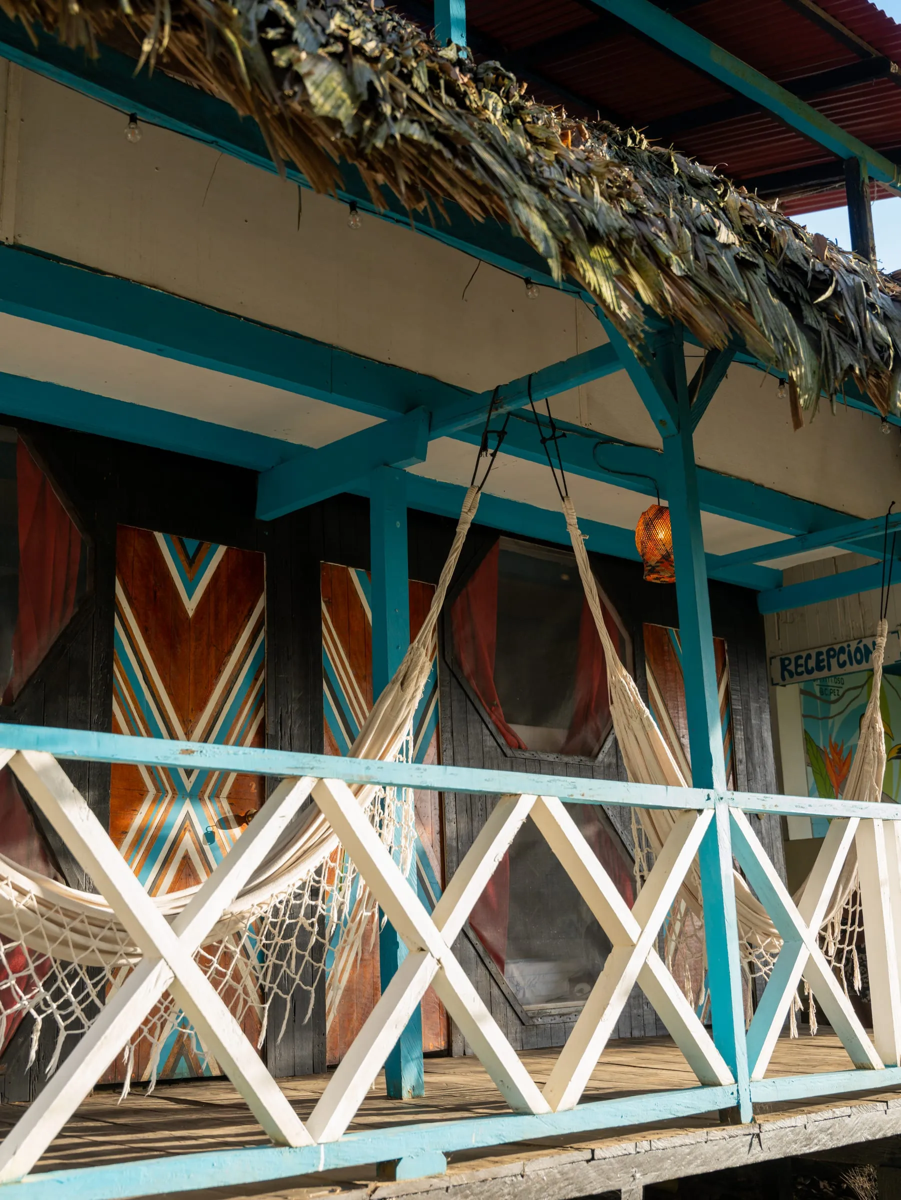 Fachada teal de Casa Azul con sus hamacas tejidas y techo de palma