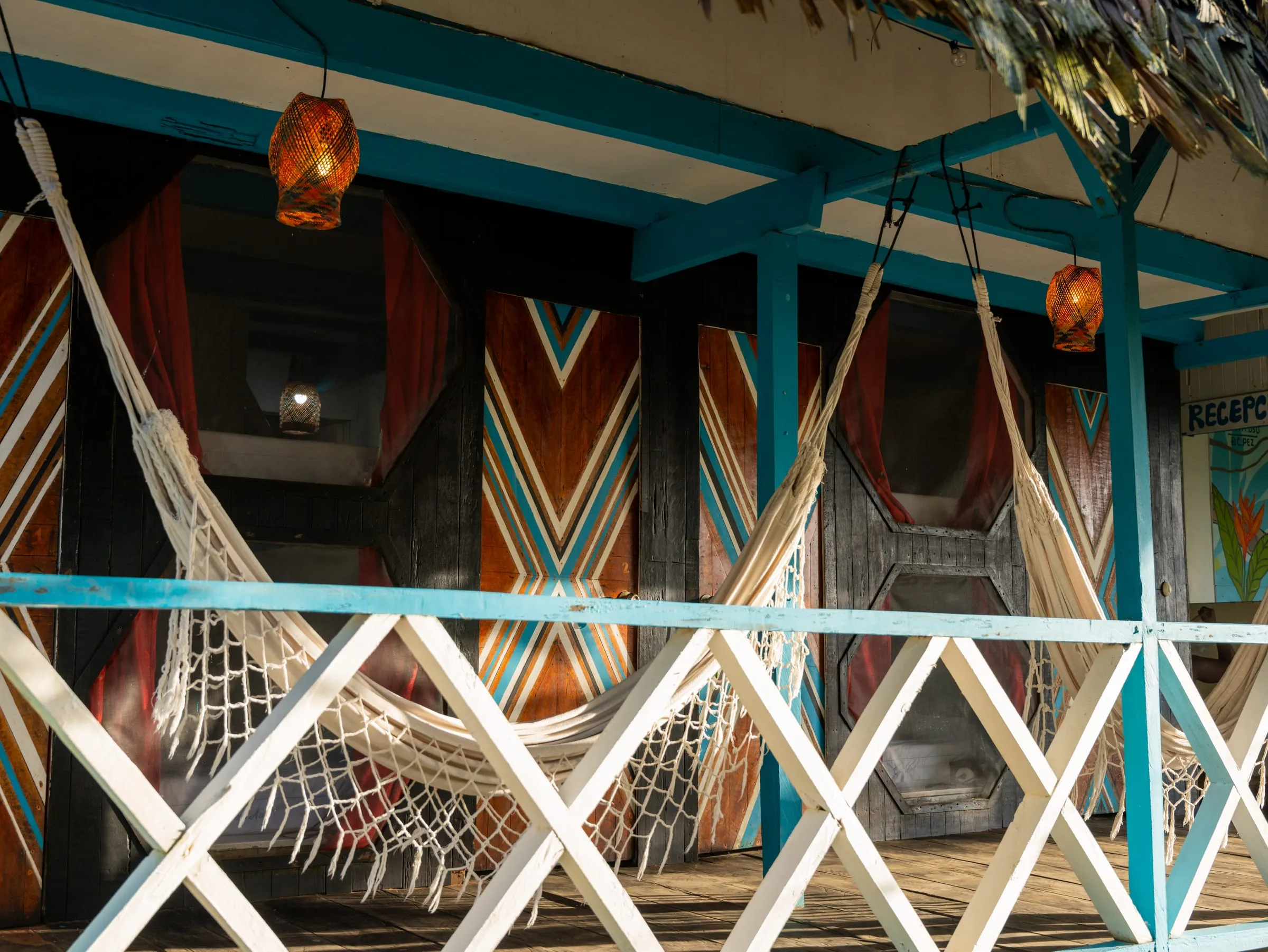 Columnas azules, hamacas y techo de palma en la fachada de Casa Azul