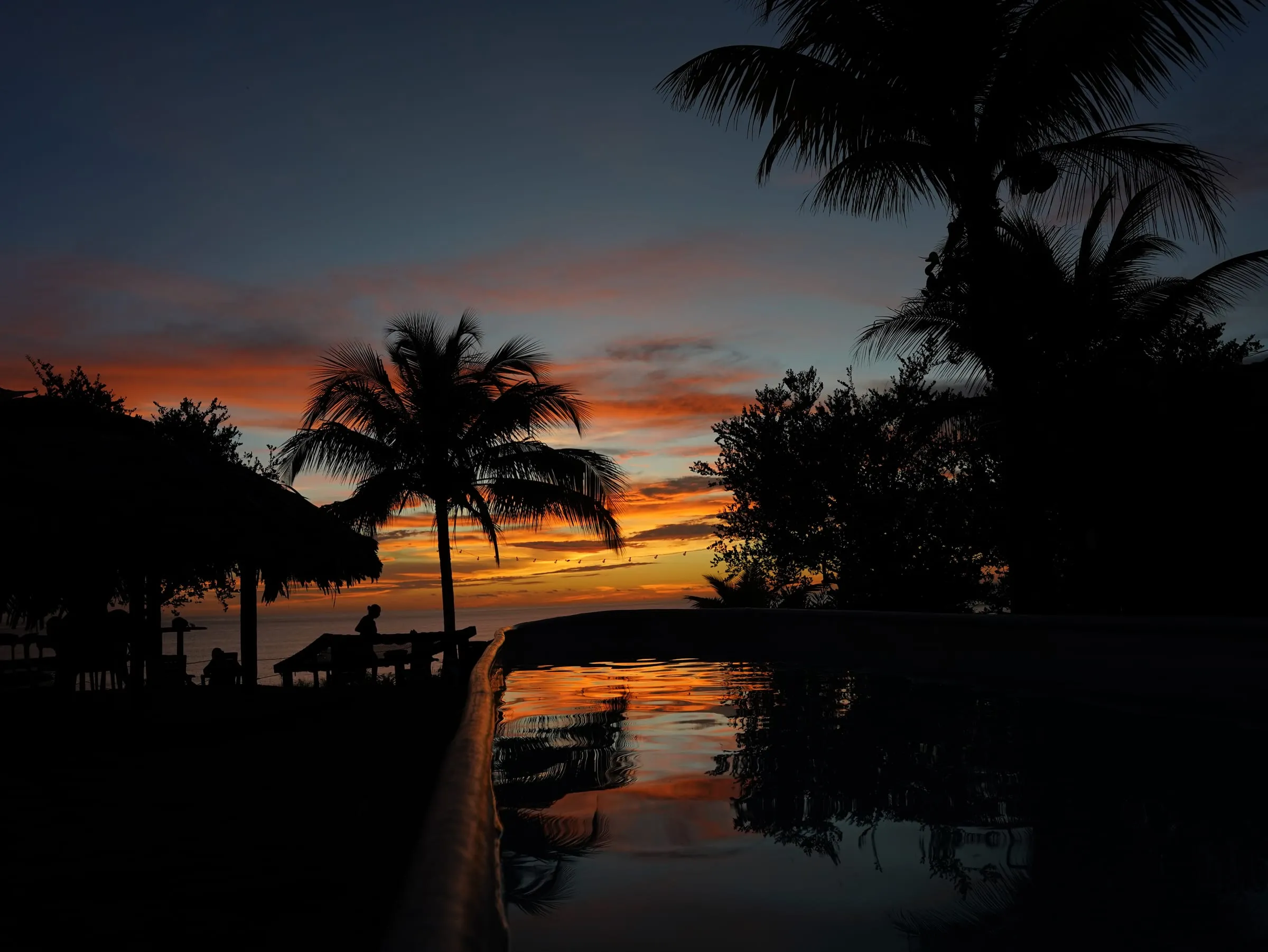 La piscina de Casa Azul reflejando el atardecer, con el mar al fondo